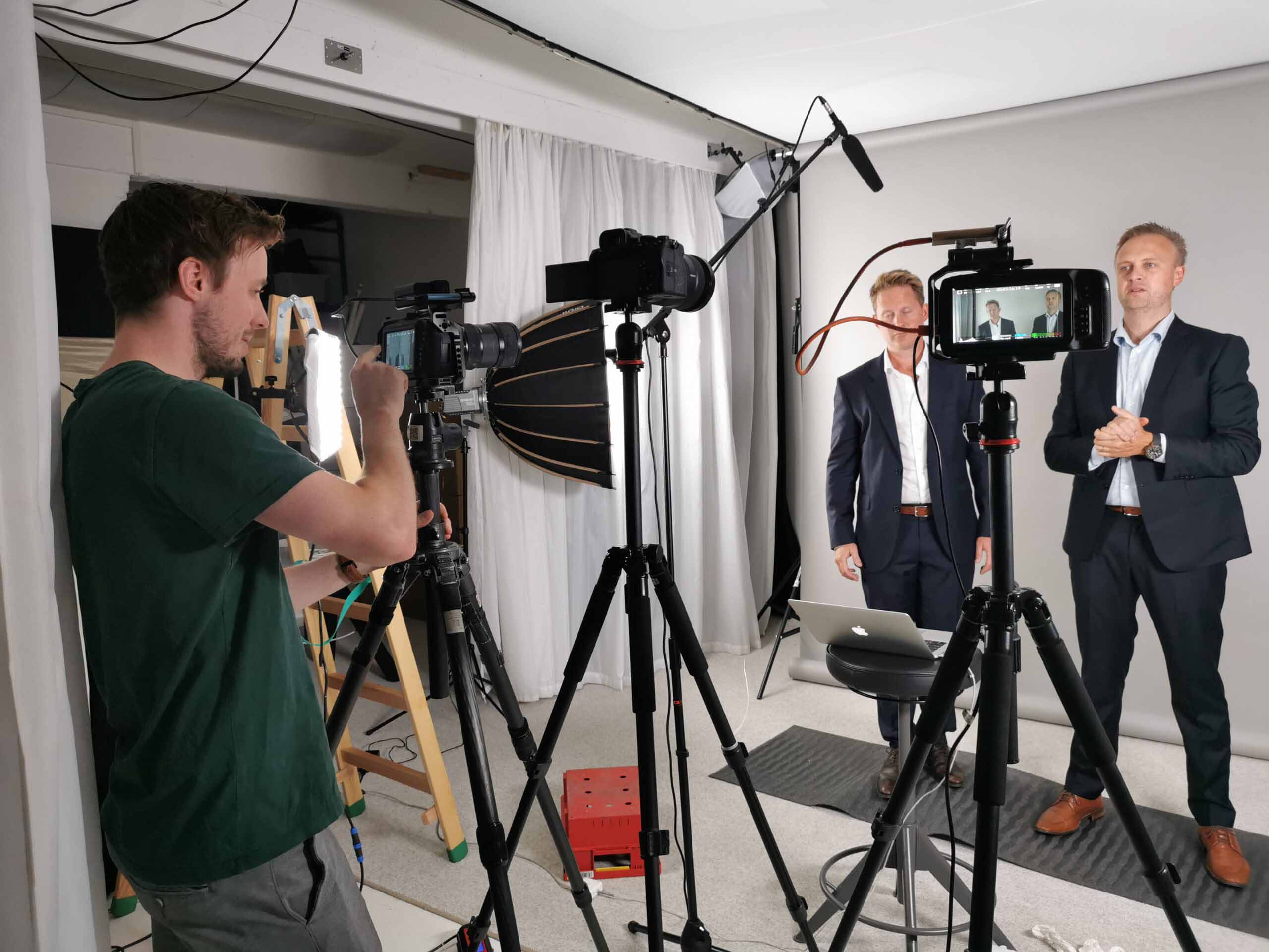 Filmopptak i studio, fotograf, lys, mikrofon, to menn i dress. Roza Pixel, brukt til innlegg om priskalkulator